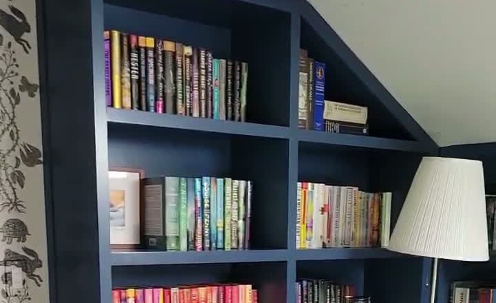 Custom navy built-in bookshelves fitted to a sloped ceiling in a Connecticut home