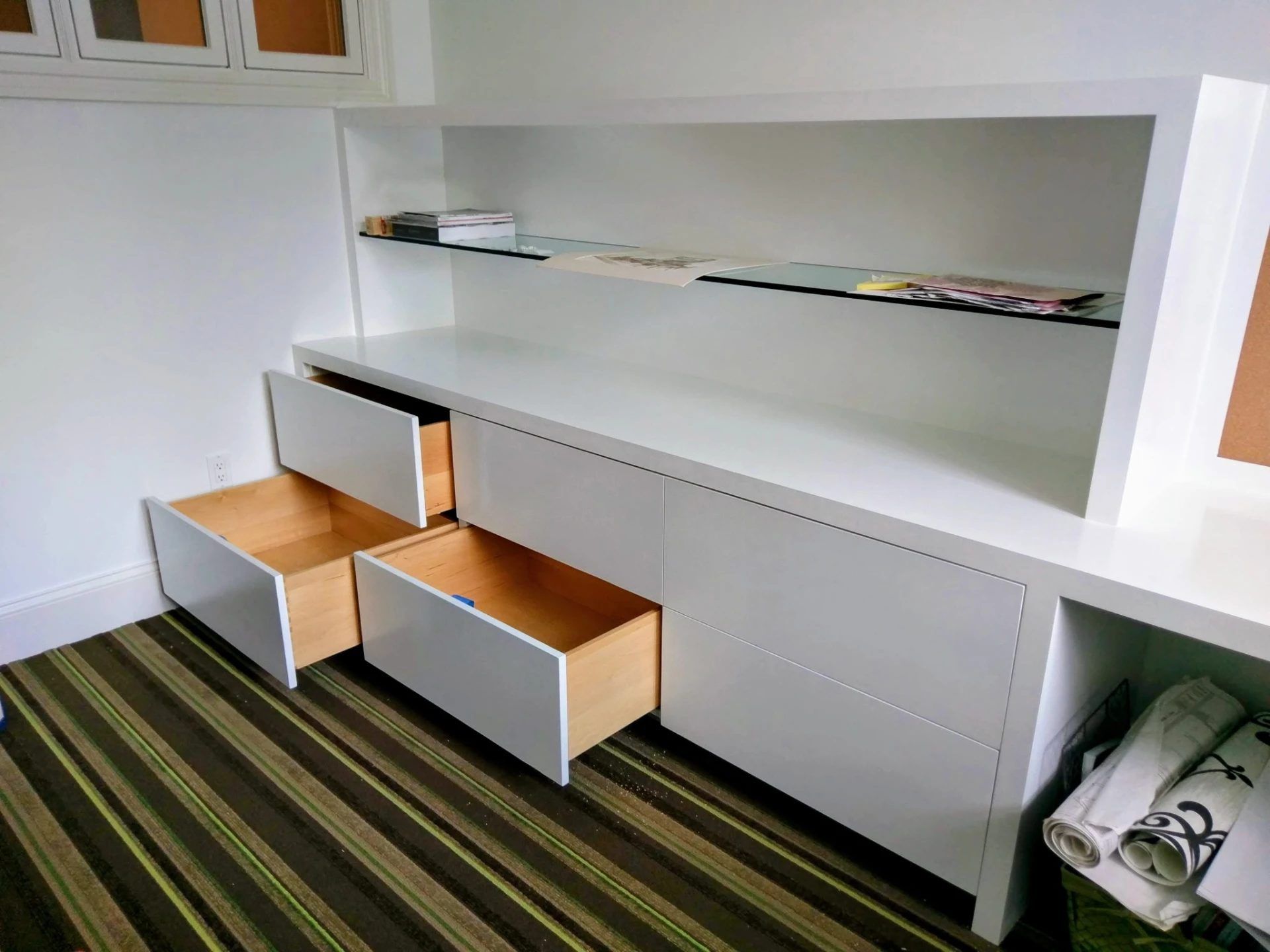 Open drawers and glass display shelving in the white built-in cabinetry of the Ridgefield, CT home office