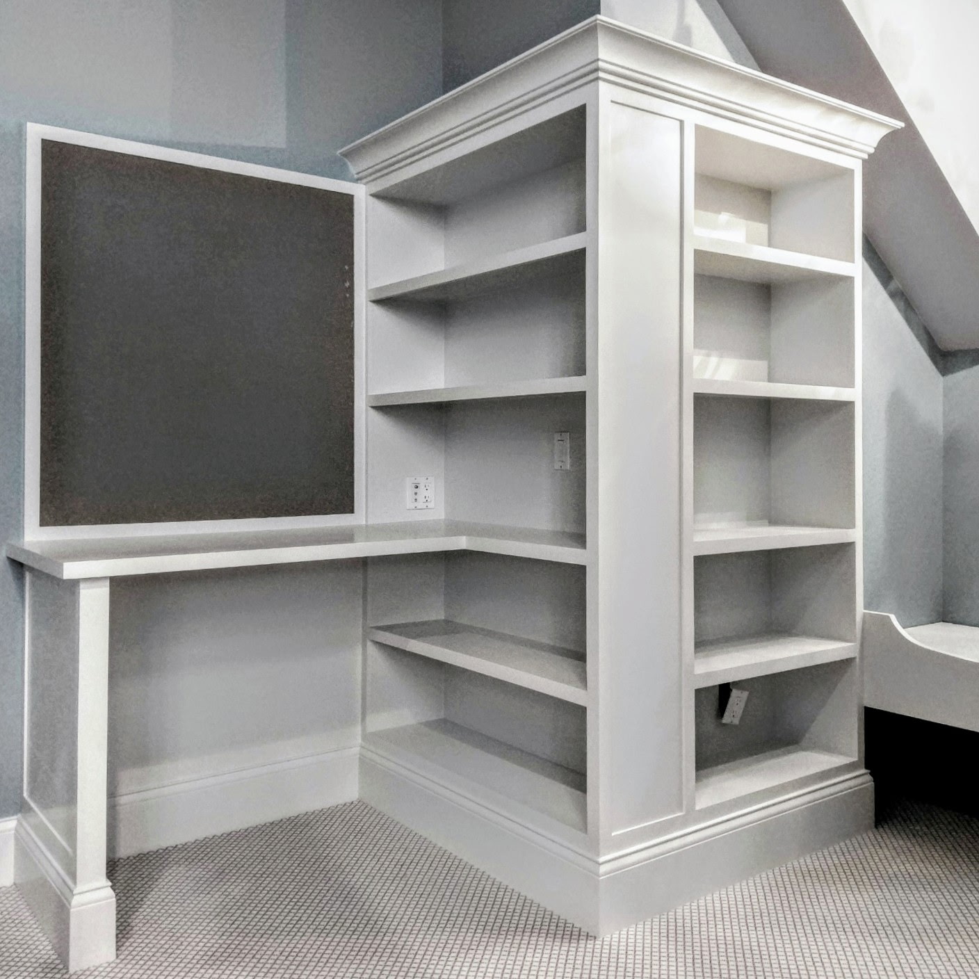 White custom built-in desk with open shelving and cabinetry in Ridgefield CT, fitted beneath a sloped ceiling by Glissmann Construction