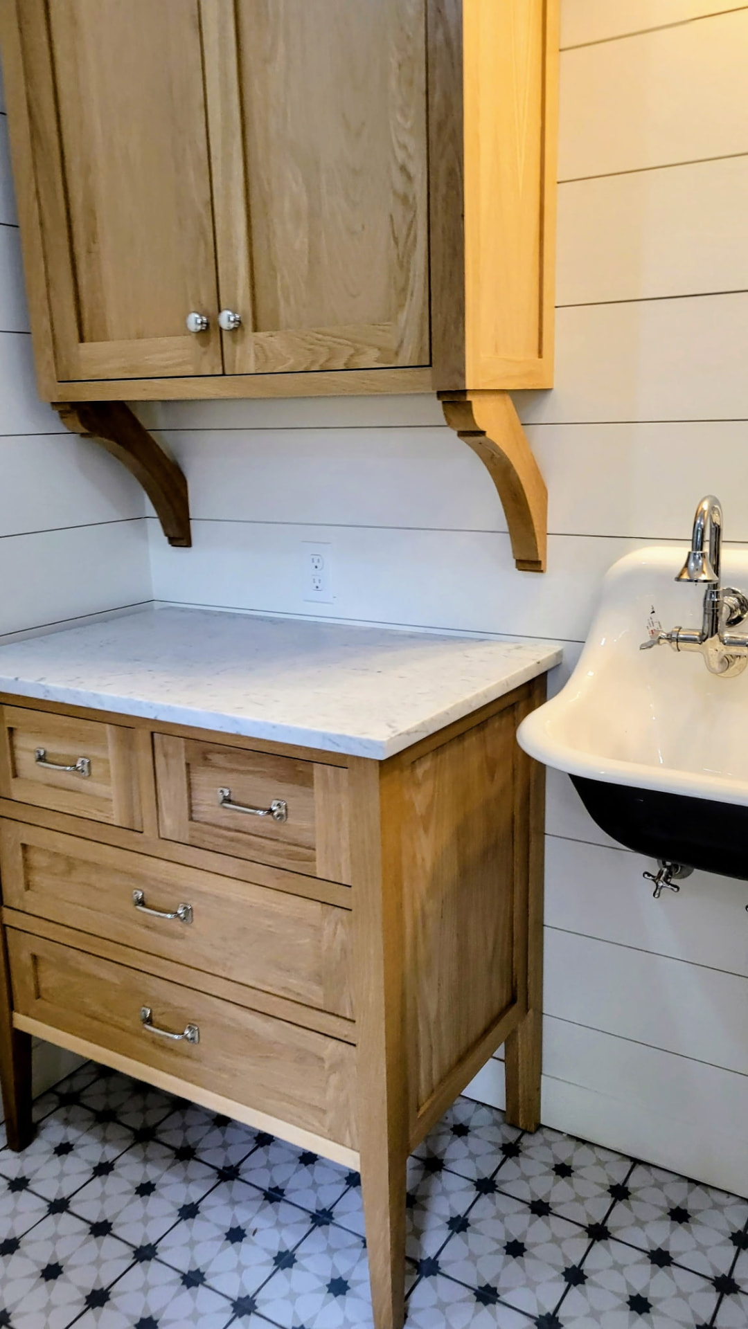 Custom oak vanity with marble top and wall cabinet on curved corbels