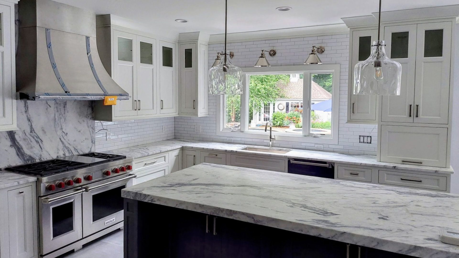 Custom kitchen cabinetry with glass-front upper cabinets and a dark island in Westchester County, NY
