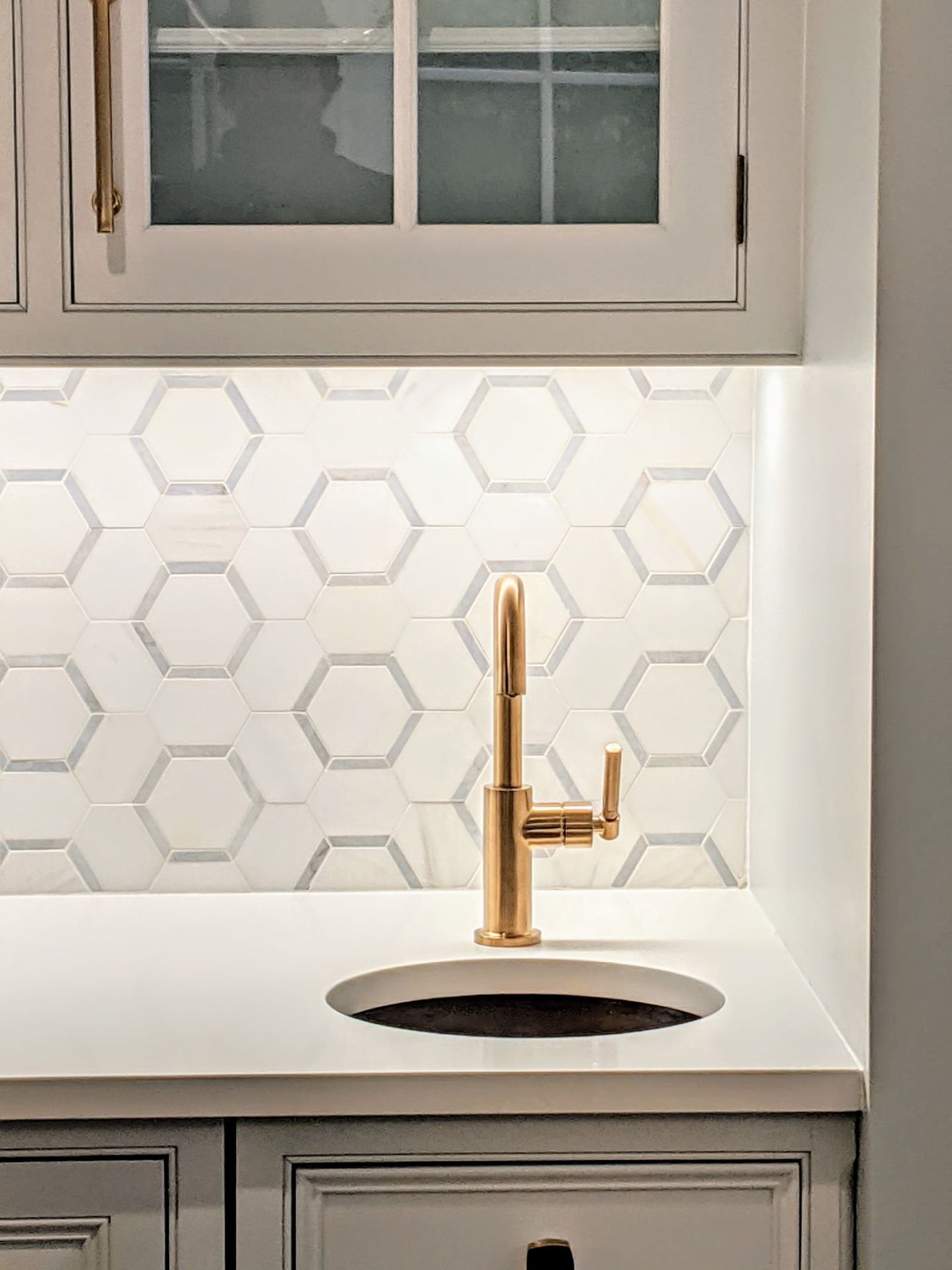 Ridgefield wet bar detail with glass-front cabinetry, a gold-tone faucet, and a geometric backsplash.