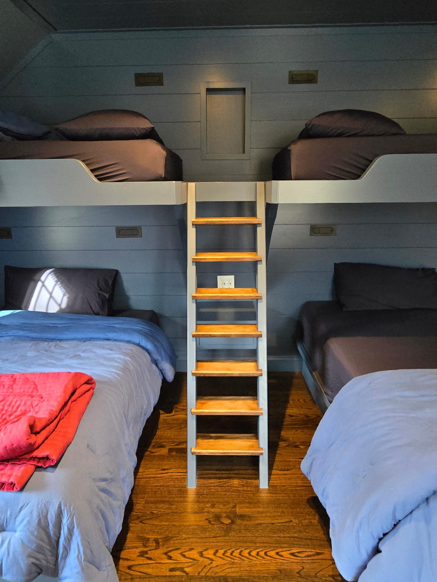 Central wooden ladder and lower berths of custom built-in bunk beds in New Canaan, CT